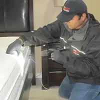 Bed bug inspection technician checking a mattress and bed frame for signs of infestation in Duluth, MN