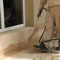 General pest control technician spraying exterior perimeter around a home in Duluth, MN