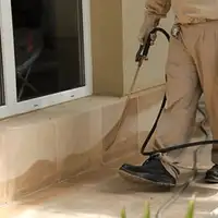 General pest control technician spraying exterior perimeter around a home in Duluth, MN