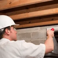 Termite inspection technician checking a basement wall and framing for termite activity in Duluth, MN