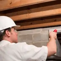 Termite inspection technician checking a basement wall and framing for termite activity in Duluth, MN